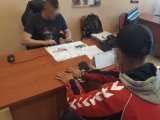 Na zdjęciu widać zatrzymanego mężczyznę, który siedzi przy biurku, a na rękach ma zapięte kajdanki. Po drugiej stronie biurka siedzi policjant, który go przesłuchuje.