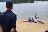 Na zdjęciu widać policjanta obserwującego plażowiczów korzystających z akwenu.
