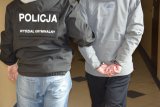 Na zdjęciu widać policjanta z wydziału kryminalnego prowadzącego zatrzymanego mężczyznę.