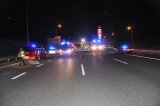 Zdjęcie przedstawia autostradę, na której znajdują się policyjne radiowozy oraz wozy strażackie z włączonymi sygnałami świetlnymi. W tle zdjęcia widać rozbity samochód osobowy biorący udział w wypadku.