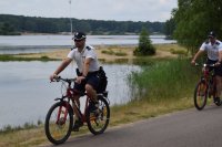 Na zdjęciu widać policjantów na rowerach patrolujących koronę zalewu Nakło-Chechło