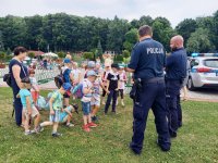 Na zdjęciu widać policjantów rozmawiających z grupą dzieci znajdującą się na terenie basenu w Radzionkowie