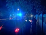 Na zdjęciu widać policyjne radiowozy z włączonymi sygnałami świetlnymi. Obok nich stoją policjanci. Przed radiowozem znajduje się zatrzymane do kontroli auto. W środku radiowozu- za kratą siedzi zatrzymany mężczyzna.