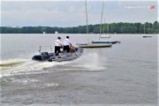 Na zdjęciu widać akwen, po którym łodzią motorową płynie policyjny patrol.