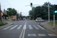 Na zdjęciu widać skrzyżowanie, które jest otaśmowane. Na skrzyżowaniu widać samochód biorący udział w zdarzeniu oraz motocykle na poboczu drogi. W tle widać policjanta i grupę osób.