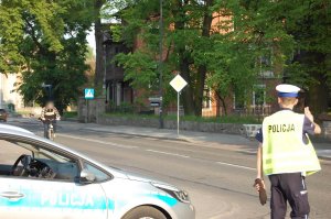 Na zdjęciu widać policjanta z drogówki, który na ulicy, zatrzymuje do kontroli rowerzystę