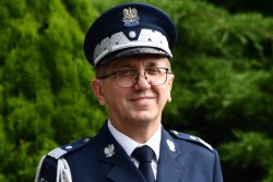 Komendant Wojewódzki Policji w Katowicach stoi na tle zieleni i się uśmiecha.