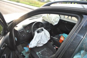 Na zdjęciu widać wnętrze samochodu osobowego. W aucie są wystrzelone poduszki powietrzne kierowcy i pasażera.
