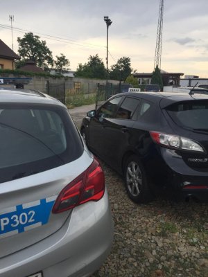Na zdjęciu widać policyjny radiowóz zaparkowany obok mazdy, której kierowca został zatrzymany do kontroli drogowej.