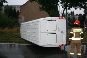 strażak a w tle przewrócony biłąy samochód dostawczy