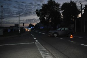 Na zdjęciu widać: na środku drogi uszkodzony samochód osobowy marki Bmw. Za samochodem widać karetkę pogotowia oraz policyjny radiowóz z włączonymi sygnałami świetlnymi.