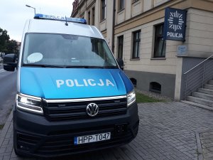 Zdjęcie kolorowe. Radiowóz oznakowany Volkswagen Crafter zaparkowany przed tarnogórską komendą Policji