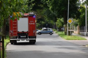wóz strażacki stojący na ulicy a w tle policyjny radiowóz stojący w poprzek