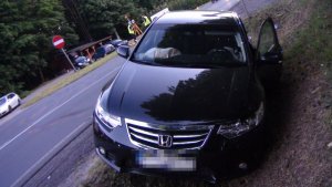 Na zdjęciu widać samochód honda, który znajduje się w przydrożnym rowie. W tle zdjęcia widać policjantów wykonujących czynności.