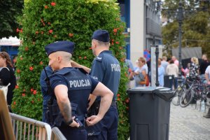 Na zdjęciu widać dwóch policjantów na tarnogórskim rynku. W tle widać uczestników imprezy.