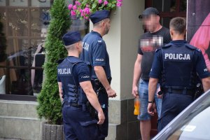 Na zdjęciu widać trzech policjantów rozmawiających z mężczyzną