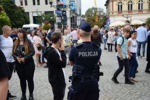 Na zdjęciu widać płytę rynku, na której policjant obserwuje przemieszczające się osoby.