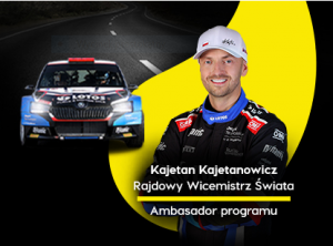 Na zdjęciu widać na czarnym tle samochód rajdowy. Obok samochodu na żółtym tle wizerunek kierowcy rajdowego i napis: Kajetan Kajetanowicz Rajdowy Wicemistrz Świata Ambasador programu.