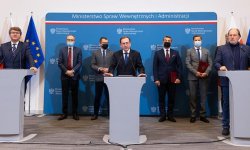 Podpisanie porozumienia ze związkami zawodowymi służb mundurowych. Na zdjęciu widać trzy mównice., przy których znajdują się  minister Mariusz Kamiński, wiceminister Maciej Wąsik oraz Rafał Jankowski – przewodniczący Zarządu Głównego Niezależnego Samorządnego Związku Zawodowego Policjantów. W tle zdjęcia widać inne osoby.