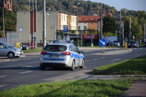 Policyjny radiowóz przemieszczający się drogą obok stadionu