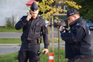 Dwóch policjantów. Jeden z nich rozmawia przez telefon
