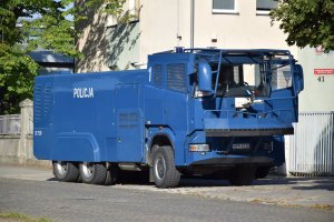 Policyjna armatka wodna zaparkowana przy ogrodzeniu stadionu piłkarskiego