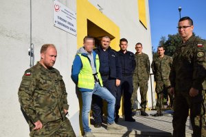 Na zdjęciu widać stojącą przy wejściu do krwiodawstwa grupę policjantów oraz żołnierzy