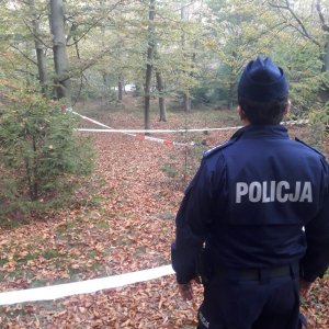 Policjant zabezpiecza miejsce znalezienia niewybuchu. Teren ogrodzony jest taśmą