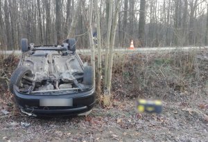 Na zdjęciu widać leżący w przydrożnym rowie, na dachu, samochód osobowy