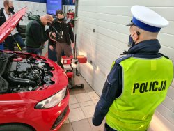 Policjant ruchu drogowego w warsztacie samochodowym przy pojeździe i operator z kamerą