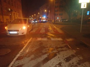 Na zdjęciu widać samochód osobowy na drodze, który zatrzymał się w połowie przejścia dla pieszych. W tle zdjęcia widać policyjne radiowozy blokujące drogę