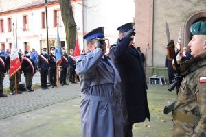 Komendant Powiatowy Policji w Tarnowskich Górach młodszy inspektor Sławomir Bylicki oraz przedstawiciel Aresztu Śledczego oddają honor przed tablicami pamięci.