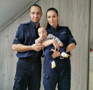 Na zdjęciu widać policjantów aspiranta sztabowego Michała Piontek oraz starszą aspirant Joannę Kmiecik-Piontek wraz z synem Aleksandrem, którego trzymają na rękach.