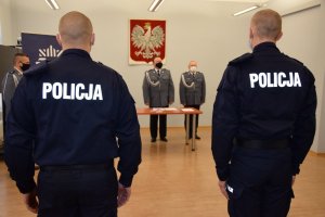 Dwóch policjantów stoi na baczność. Przed nimi znajdują się szef i wiceszef tarnogórskich policjantów.