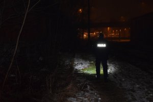Policjant świeci latarką i sprawdza opuszczone budynki znajdujące się nieopodal dworca kolejowego.