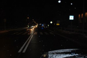 Przejście dla pieszych. Za nim stoi policjant, który wstrzymał ruch na drodze.