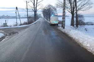 Na zdjęciu widać drogę, przy której stoi policyjny radiowóz. Okolica jest cała zaśnieżona.