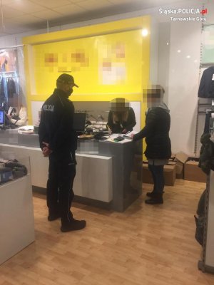 Na zdjęciu widać policjanta, który wraz z pracownikiem sanepidu, w sklepie,  sprawdza przestrzeganie zasad reżimu sanitarnego.