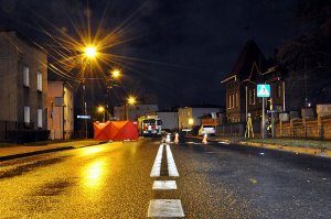 Na zdjęciu widać drogę, na której widać przejście dla pieszych. Widać również czerwony parawan oraz wóz strażacki.