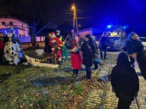 Grupa osób. Niektóre z nich przebrane za różne postacie w tym Świętego Mikołaja. Wśród nich znajduje się policjant, a w tle widać policyjny radiowóz.