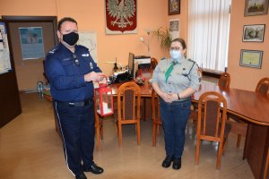 Komendant trzyma latarenkę z Betlejemskim Światłem Pokoju. Obok niego stoi harcerka.