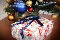 Na zdjęciu widać choinkę, pod którą leży prezent