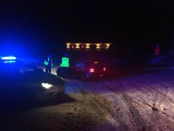 Policjanci ruchu drogowego po zmroku, ubrani w kamizelki odblaskowego kontrolują volkswagena.