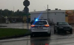 Na zdjęciu widać policyjny radiowóz z włączonymi sygnałami świetlnymi. Obok znajduje się kontrolowany samochód osobowy.
