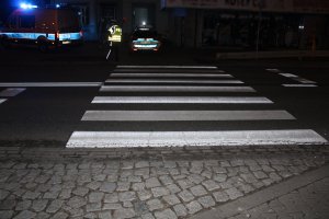 Przejście dla pieszych. Po drugiej stronie przejścia widać policjanta oraz policyjny radiowóz