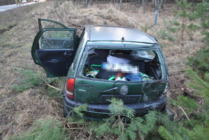Na zdjęciu widać zniszczone auto znajdujące się w przydrożnym rowie. Samochód ma wybitą tylną szybę oraz uszkodzoną karoserię.