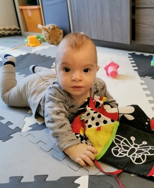 na zdjęciu widoczny mały Olek raczkujący, w tle zabawki i meble