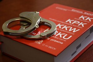 na zdjęciu widoczny zbiór kodeksów w czerwonej oprawie, na nim kajdanki