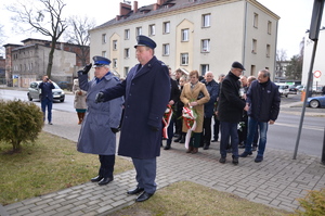 przedstawiciele służb mundurowych, władz miasta i powiatu i mieszkańcy pod pamiątkową tablicą przed budynkiem komendy policji