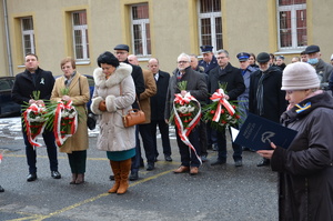 przedstawiciele służb mundurowych, władz miasta, powiatu, posłowie i mieszkańcy pod pamiątkową tablicą przed budynkiem aresztu